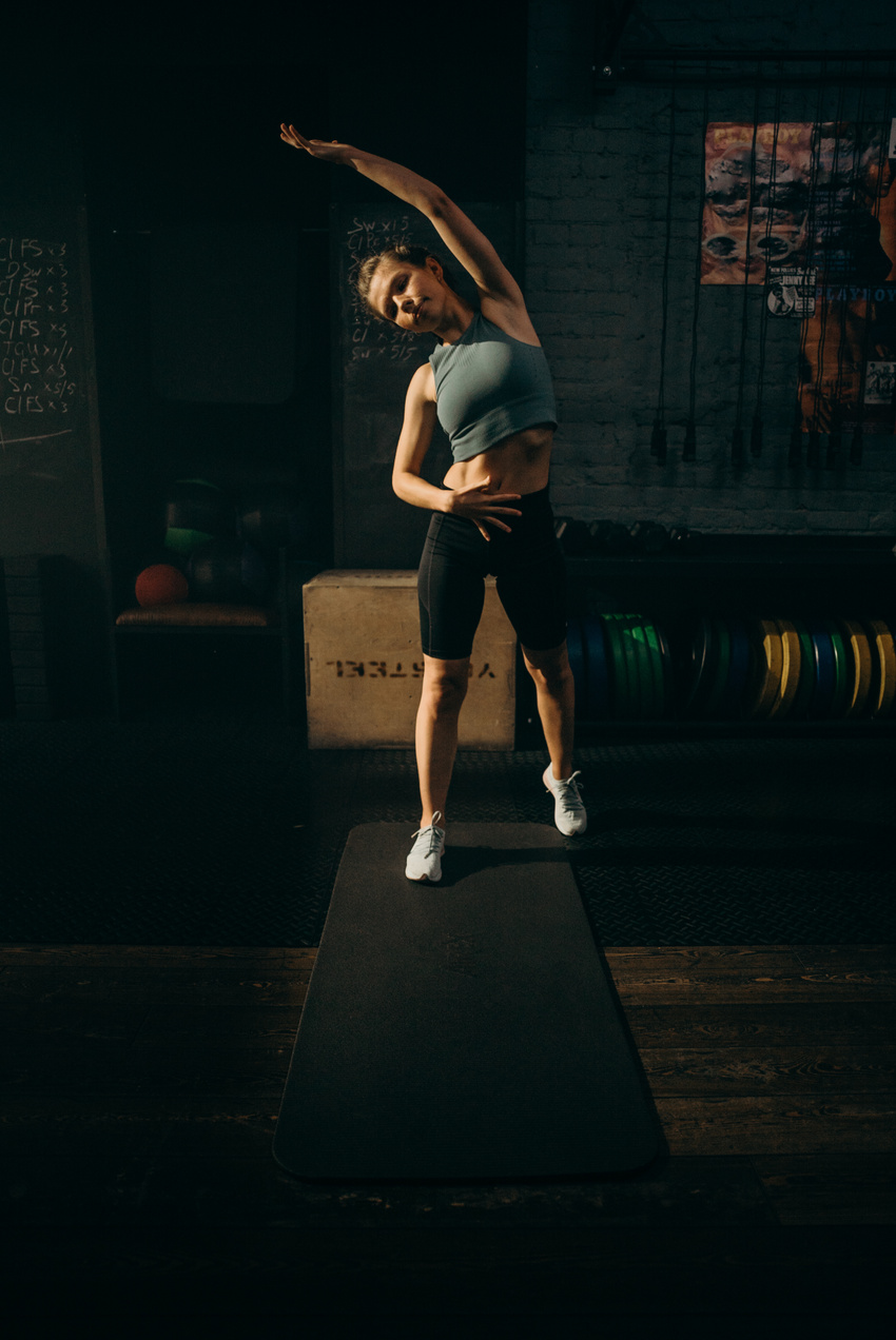 Woman in Gray Sports Bra and Black Shorts Running on Black Wooden Floor